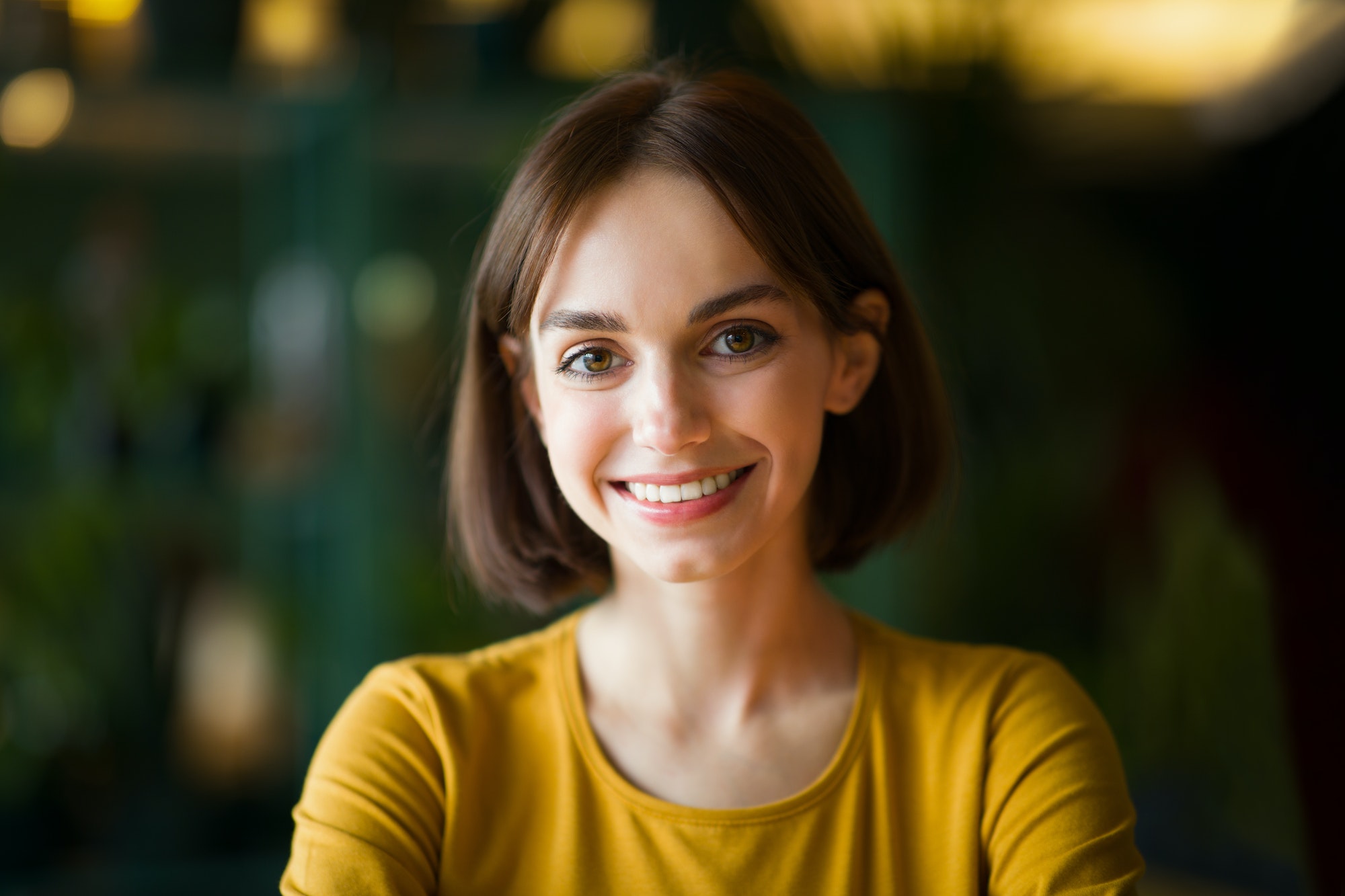 Portrait of beautiful cheerful young brunette woman smiling at camera